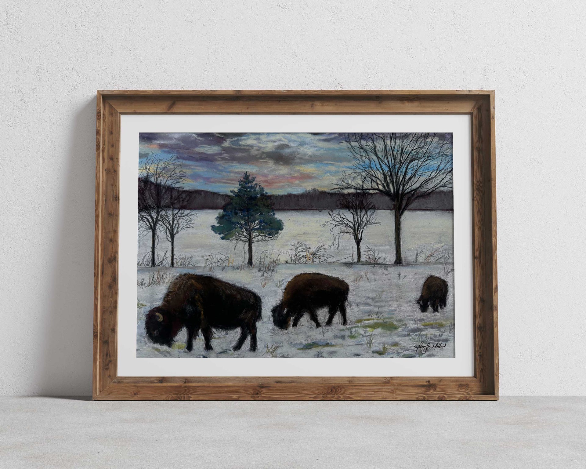 This soft pastel painting of bison grazing in the winter snow is displayed in a wood frame with a white mat.