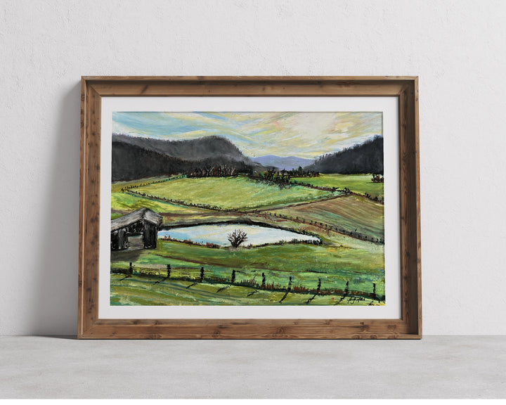 A print of an oil pastel painting of farmland off Red Lick Road in a wood frame and white mat.